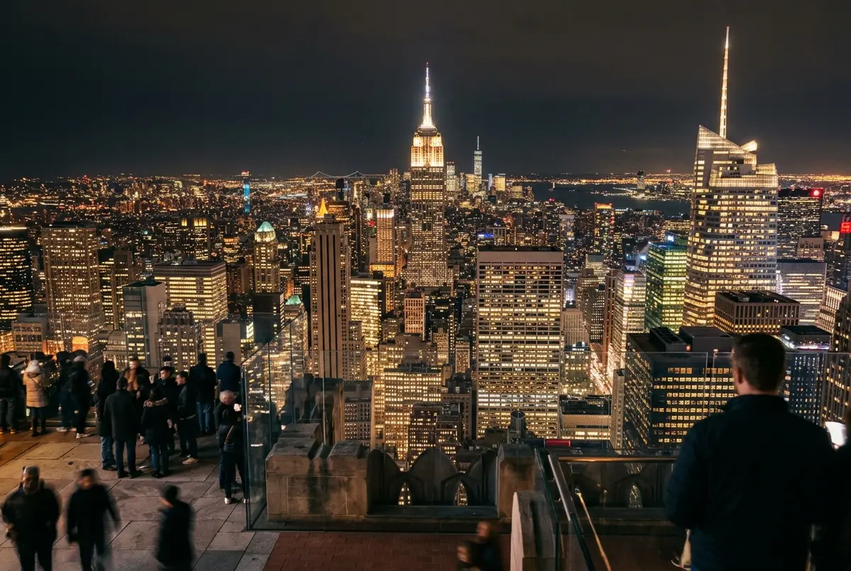 manhattan skyline lit up at night seen from the top of the rock observation deck open air terrace with the empire state building glowing in the distance